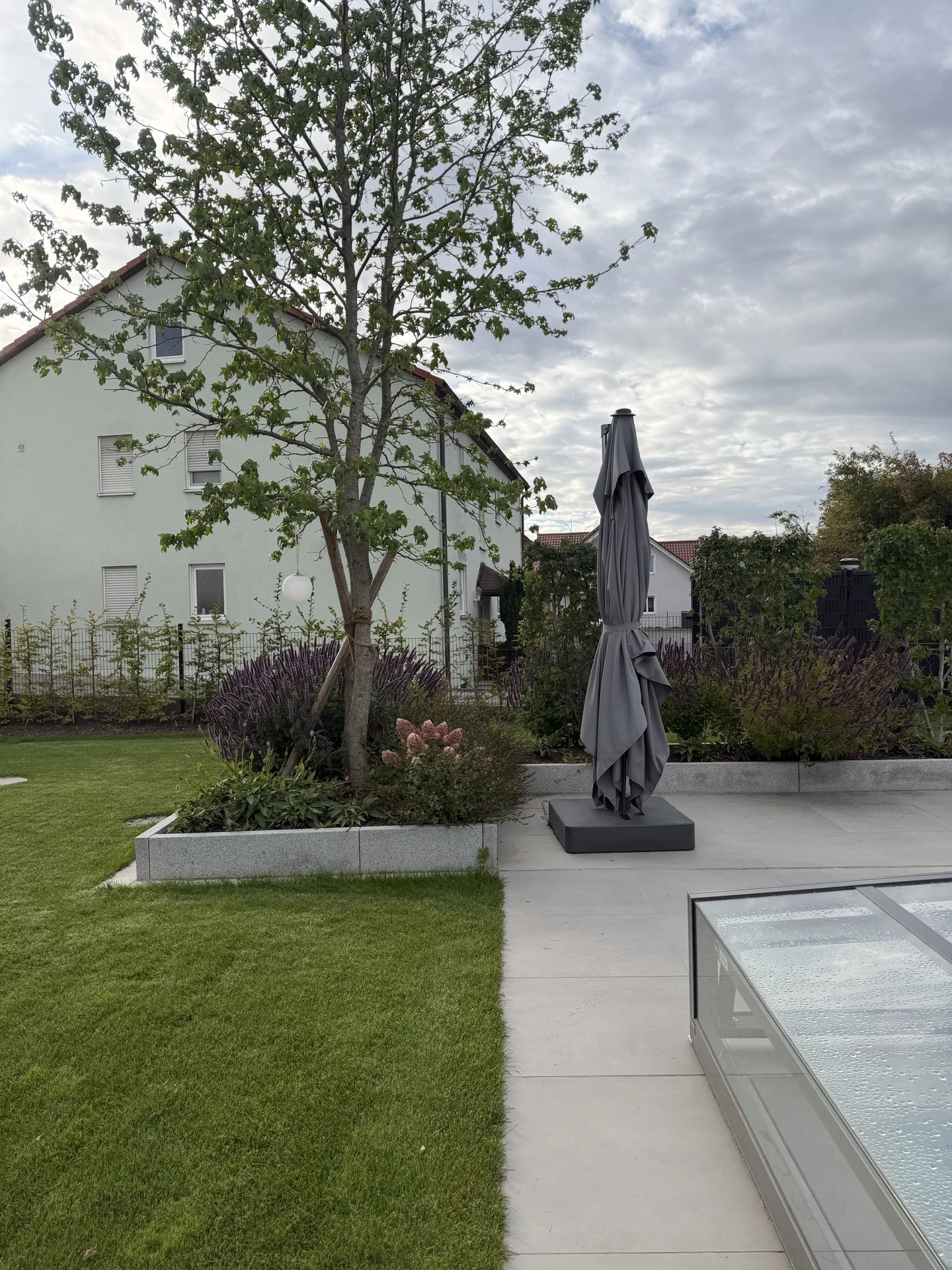 Terrassenbelag und Pflanzbeet neben einer überdachten Poolanlage